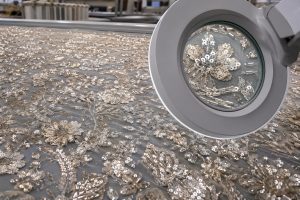 High-density embroidered sequin fabric inspected for stitch precision