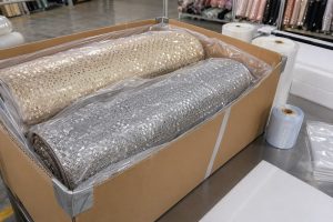Protective export packaging for champagne and silver sequin fabric rolls