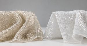 Champagne sequin fabric on a soft chiffon base draped beside a white sequin fabric on a crisp organza base on a white lab surface