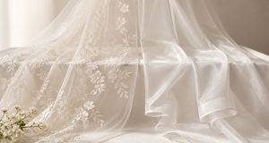 Ivory bridal veil fabrics compared: sheer embroidered mesh and smooth organza draped over a white studio table with white flowers