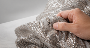 Professional buyer hand inspecting the texture of high-quality sequined embroidery fabric