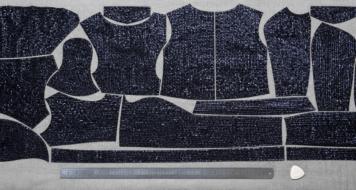 Sequin fabric laser cutting layout with tightly nested garment pieces on a cutting table