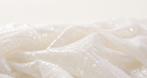 Pearly white shimmering sequins on ivory mesh fabric in soft focus
