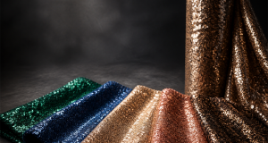 Fanned sequin fabric swatches in emerald, sapphire, champagne and rose gold beside a rolled sequin bolt for 2026/27 market quality and customization sourcing