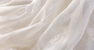 Semi-transparent white organza with delicate embroidery in soft layered folds
