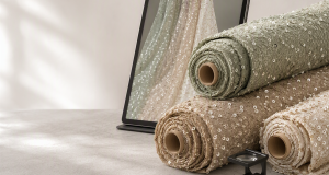Recycled sequin fabric rolls in sage, sand and champagne tones beside a tablet with a digital fabric swatch render and an inspection loupe for sustainable B2B sourcing and quality control